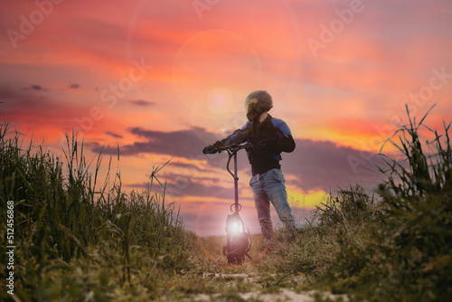 concept of transport of the future, a man in a helmet and gear on an electric scooter at sunset in a field.