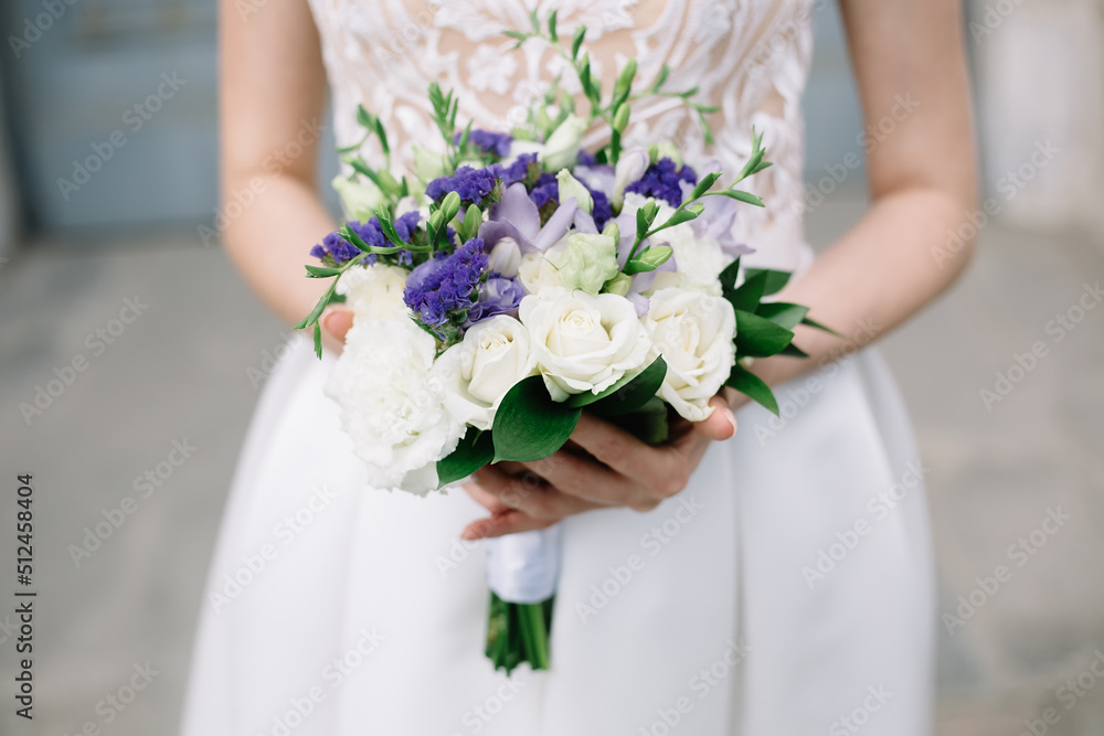 Wedding bouquet with white and violet roses in hands of beautiful bride in retro stylish wedding dress. Selective focus. High quality photo. Wedding bouquet with white and violet roses in hands of beautiful bride in retro stylish wedding dress. Selective focus. High quality photo.