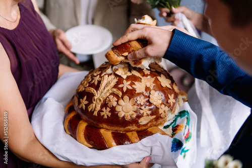 Traditional wedding Ukrainian bread korovai with flowers at ceremony, ancient symbol of hospitality and unity. Ukrainian bread and salt welcoming tradition when bride and groom take a piece of bread