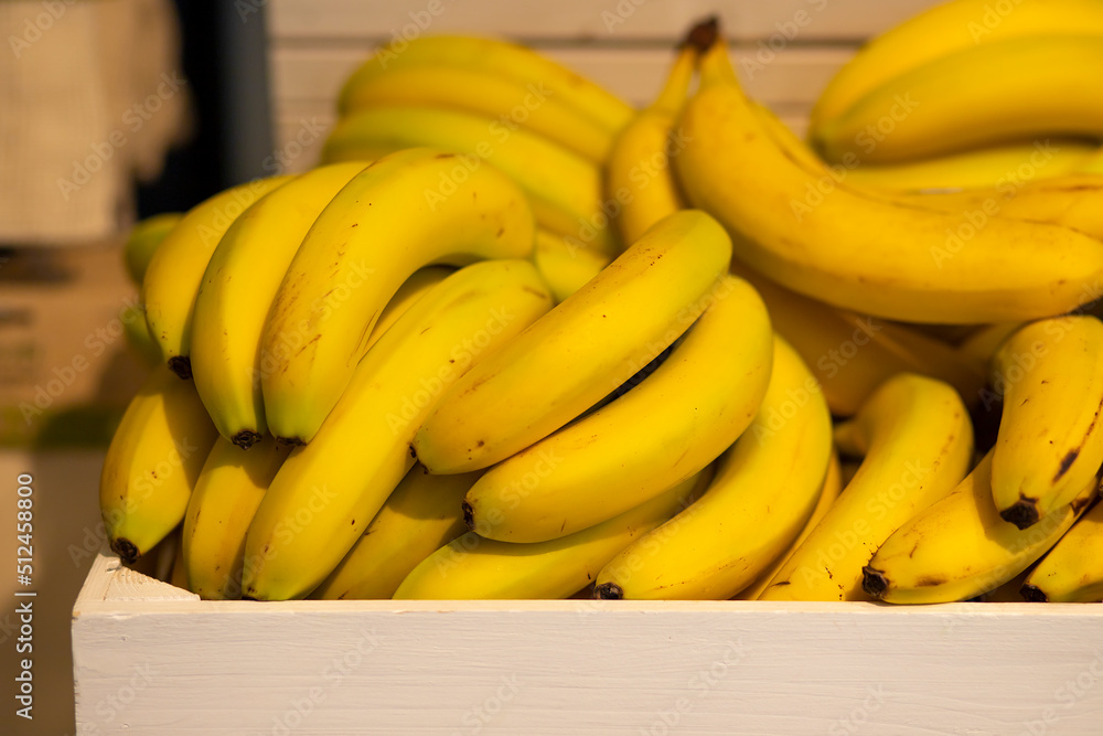 A vibrant photo of a bunch of bananas being sold at the market in a stylish vintage wooden box. Bright photos for advertising and magazine covers