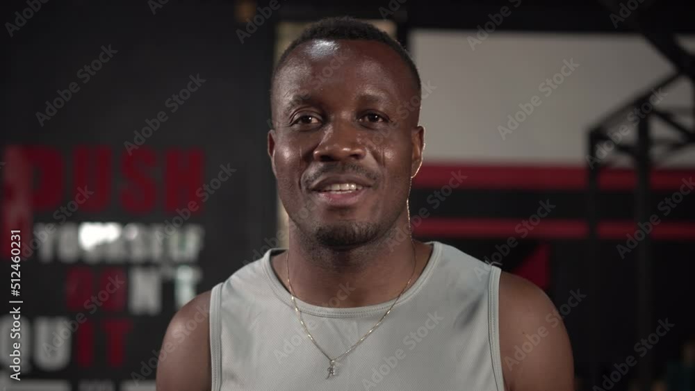 Smiling friendly athletic man standing in a gym after a workout and looking at the camera, Sport and fitness concepts Smiling friendly athletic man standing in a gym after a workout and looking at the camera, Sport and fitness concepts