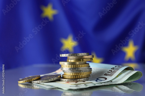 Coins and banknotes on table against European Union flag, space for text photo