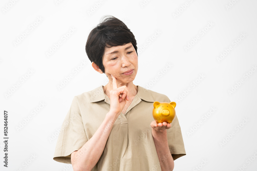 ブタの拠金箱を持って悩むミドル女性 ブタの拠金箱を持って悩むミドル女性