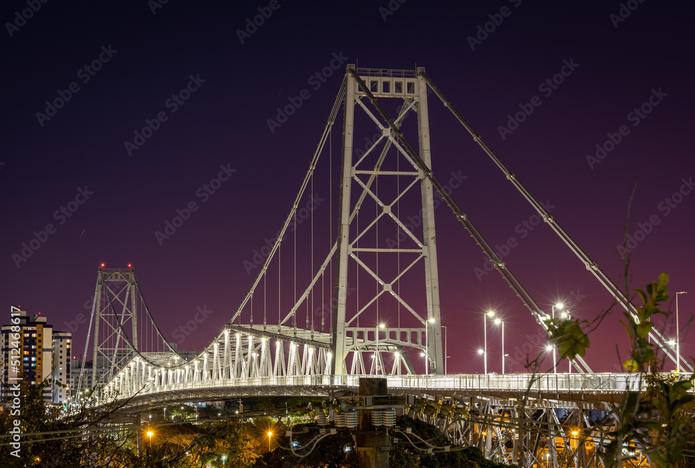 Naklejka premium Night view of the Hercilio Luz suspension bridge. The longest suspension bridge in Brazil and the symbol of the city of Florianopolis. Design engineering structure bridge at night. Illumination of the
