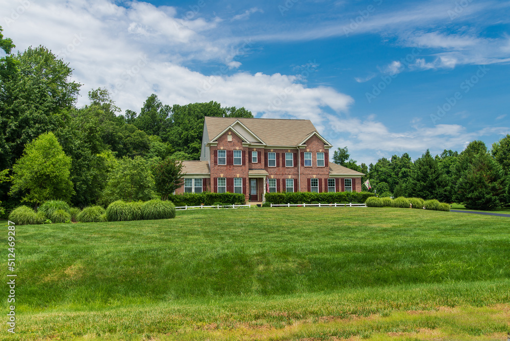  large traditional red brick colonial house on a green lawn in Virginia.