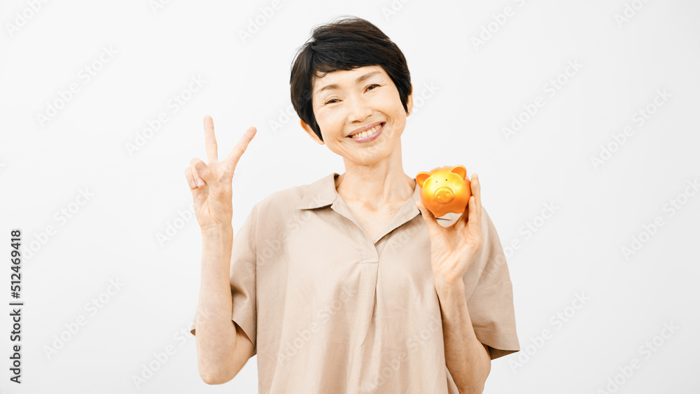 ブタの貯金箱を持ってピースサインをするミドル女性