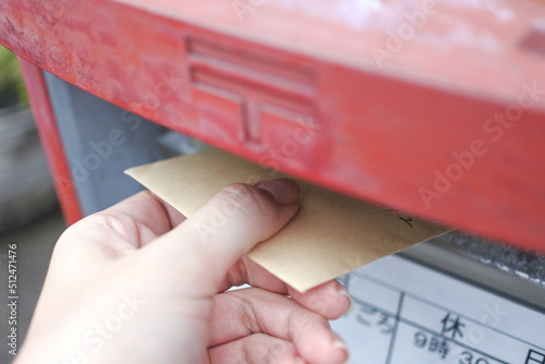 郵便ポストに封筒を入れる