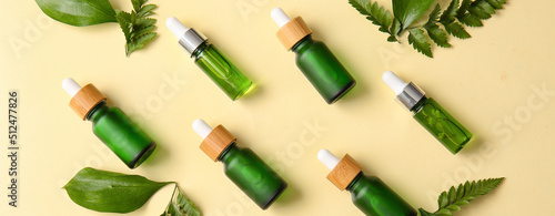 Many bottles of natural cosmetic serum and essential oils on color background, top view