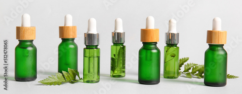 Different bottles of natural cosmetic serum on light background