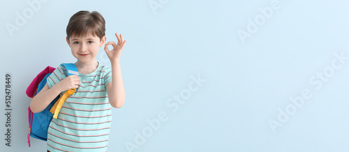 Canvastavla Cute little schoolboy showing OK on light blue background with space for text
