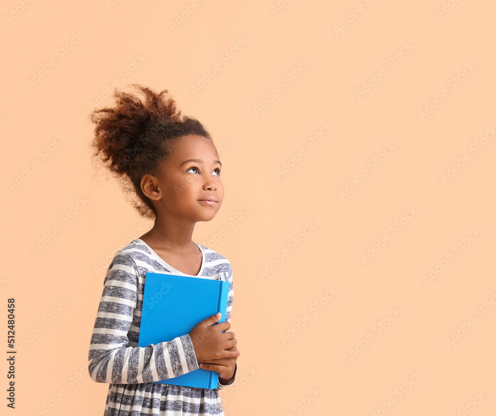 Little African-American girl with book on beige background Little African-American girl with book on beige background