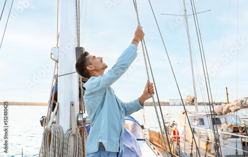 Young man adjusting the rigging of his yacht