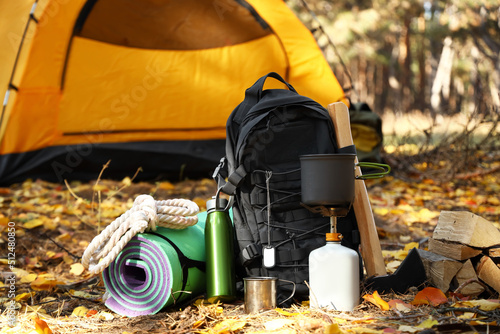 Fotobehang Tourist's survival kit and camping tent in autumn forest