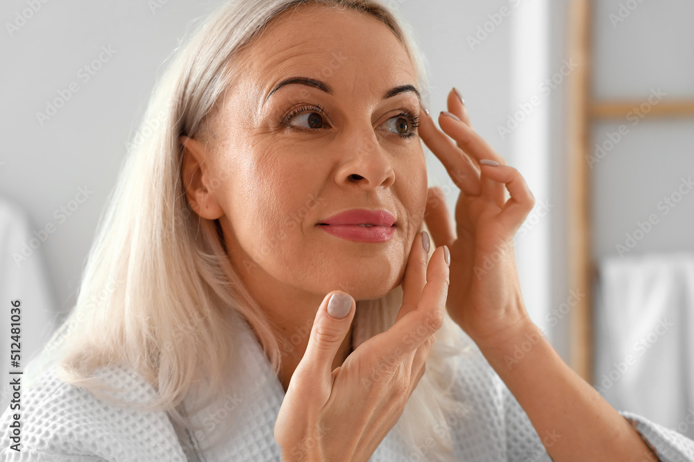 Morning of mature woman giving herself facial massage at home Morning of mature woman giving herself facial massage at home