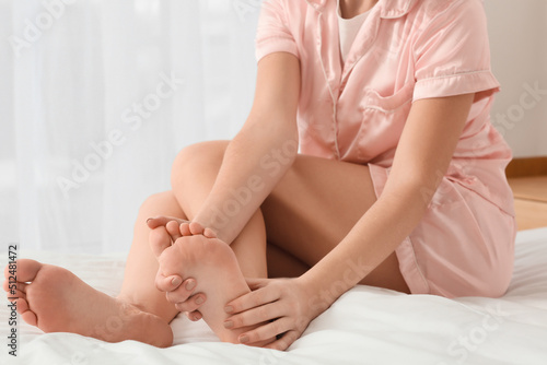 Young woman making foot massage on bed, closeup