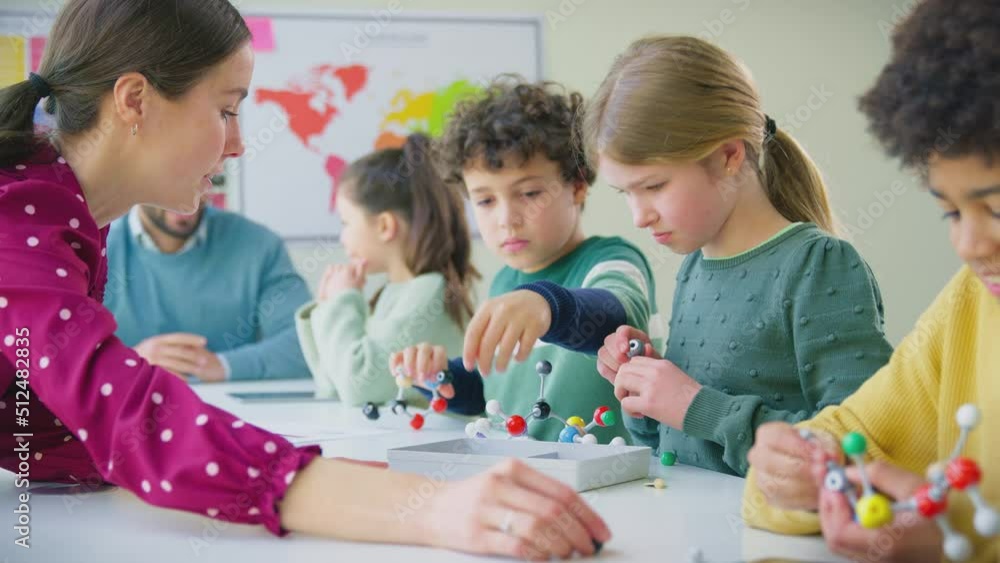 Multi-cultural students with teachers in classroom studying molecular model in science class - shot in slow motion Multi-cultural students with teachers in classroom studying molecular model in science class - shot in slow motion