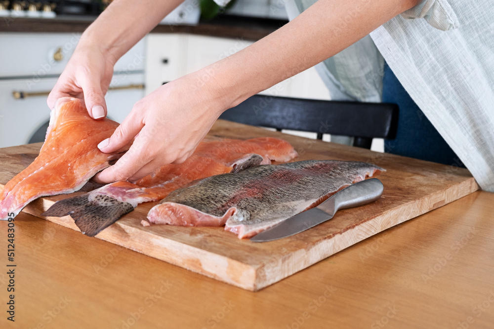 Female hands cutting fillet of red fish. Red caviar. Removing fish bones. Butchering red fish meat...Food concept.