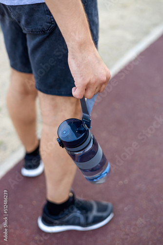 close-up of a man doing sports, holding a sports water bottle in his hands