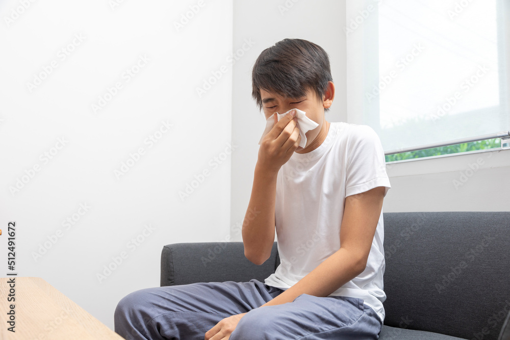 Sick Asian preteen boy blowing nose and sneeze at home, healthcare concept. Sick Asian preteen boy blowing nose and sneeze at home, healthcare concept.