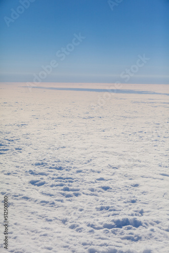 Airplane flight. Wing of an airplane flying above the clouds. View from the window of the plane. Airplane  Aircraft. Traveling by air. Aircraft s wing and land seen through the illuminator. 