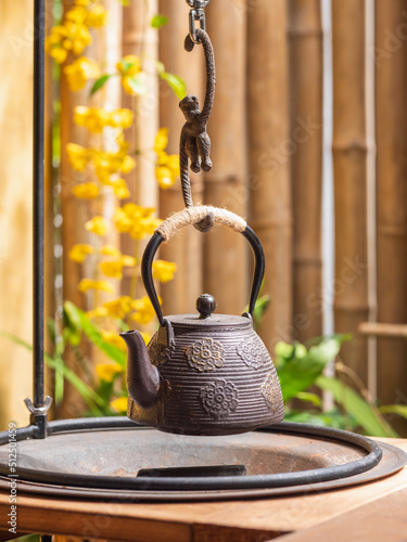 Japanese tea kettle hanging over a chacoal stove. Cast iron teapot hanging over the stove. Japannese style tea kettle. photo