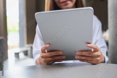 Closeup image of a young woman holding and using digital tablet