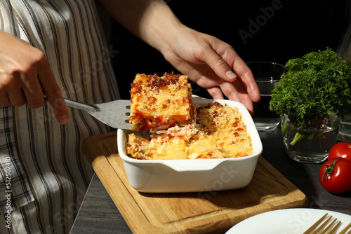 Woman takes Lasagna from the plate, close up
