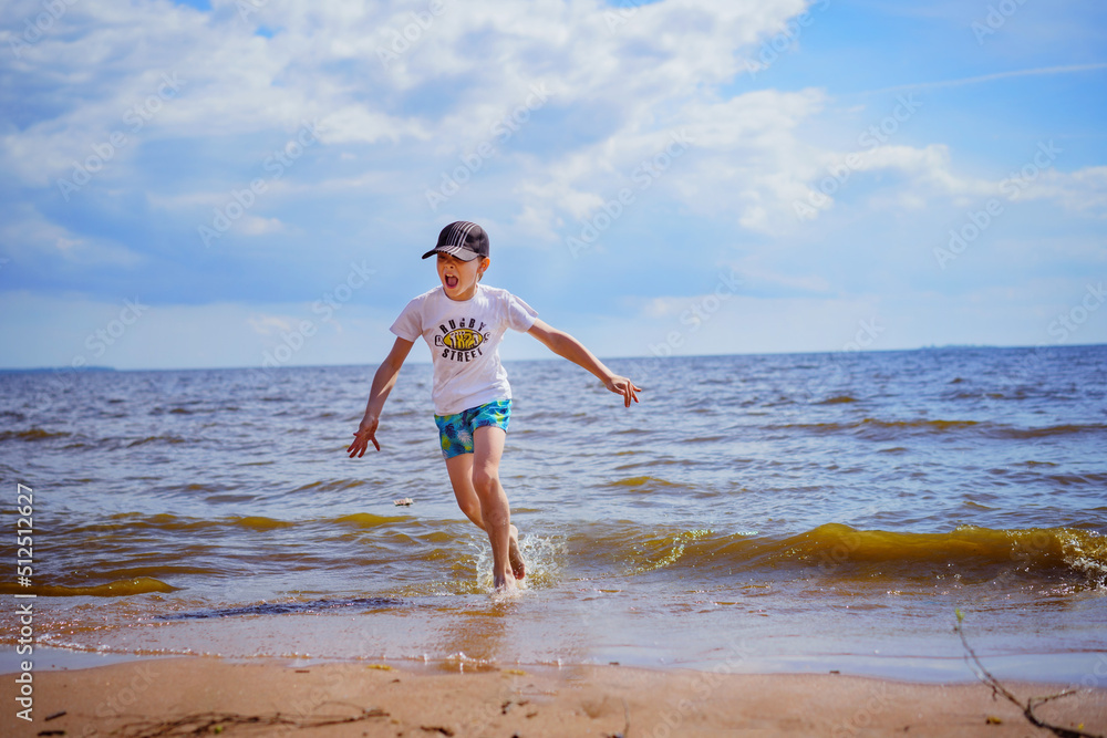 Happy little boy is running in the sea on sunny summer day. Childhood concept Happy little boy is running in the sea on sunny summer day. Childhood concept