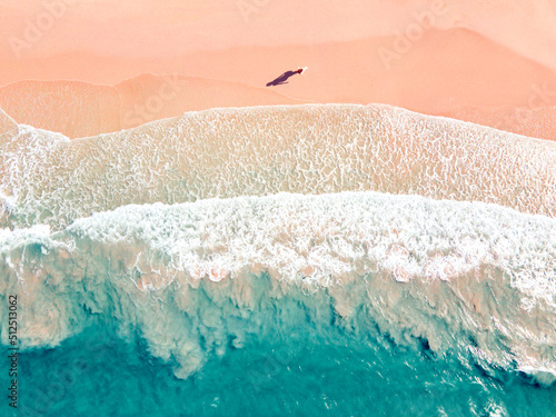 Aerial view of young female felling fun and free on beach at sunrise. Happy tourist woman on summer vacation. Tropical Beach. Top view.