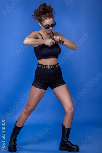 beautiful young woman with curly hair with a gun on a blue background