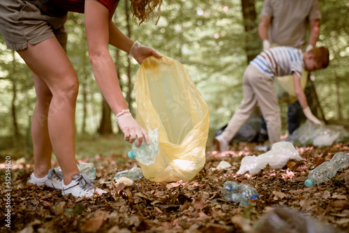 Close up of woman's hand picking up plastic bottle from forest