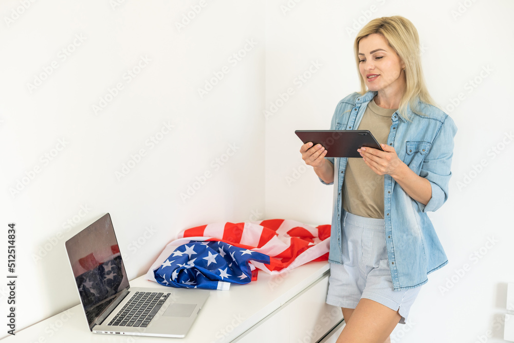 Happy woman employee sitting wrapped in USA flag, shouting for joy in office workplace, celebrating labor day or US Independence day. Indoor studio studio shot isolated on yellow background Happy woman employee sitting wrapped in USA flag, shouting for joy in office workplace, celebrating labor day or US Independence day. Indoor studio studio shot isolated on yellow background
