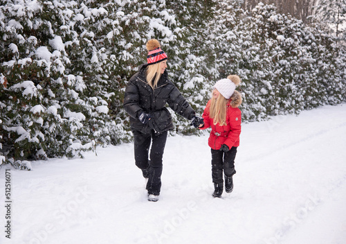 beautiful blonde mother with daughter having fun in winter park