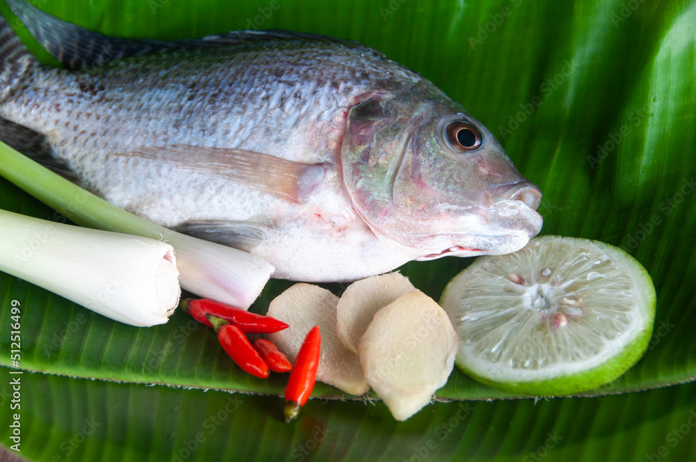 To view of fresh tilapia fish with lemongrass, lemon and chili on banana leaf.