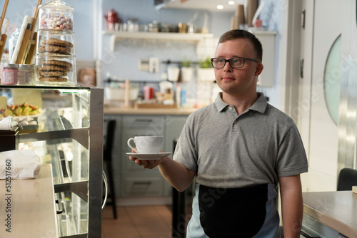 Caucasian man with down syndrome walking and carrying a cup of coffee