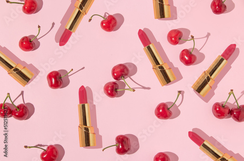 Summer creative pattern with bright red cherries and golden lipstick on pastel pink background. 80s or 90s retro aesthetic idea. Minimal summer fashion idea. photo