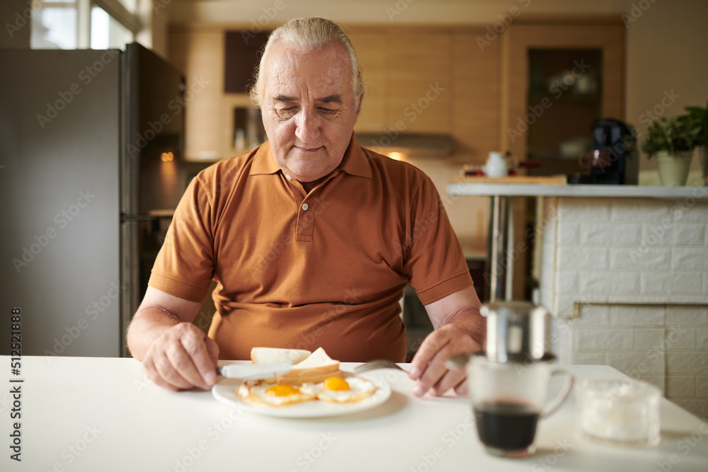 Senior man eating fried eggs with bread and coffee for breakfast at home Senior man eating fried eggs with bread and coffee for breakfast at home