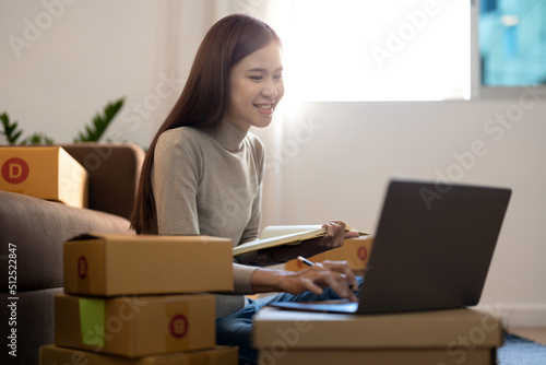 Asian woman Running Business From Home. Shipping shopping online, young start up small business owner packing cardboard box at workplace. Online selling or e-commerce © Natee Meepian