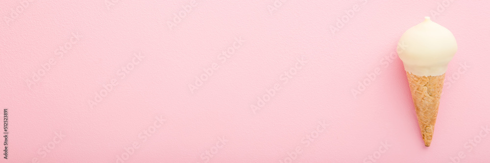 Waffle cone of white vanilla ice cream on light pink table background. Pastel color. Wide banner. Closeup. Cold sweet snack in summer. Empty place for text. Top down view. Waffle cone of white vanilla ice cream on light pink table background. Pastel color. Wide banner. Closeup. Cold sweet snack in summer. Empty place for text. Top down view.