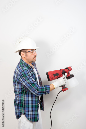 Male builder with electric spray gun on white background