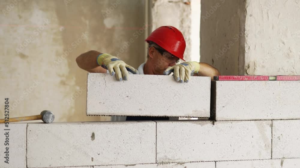 Bricklayer or mason lays bricks to construct wall of autoclaved aerated ...