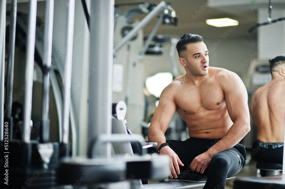 Fototapeta premium Muscular arab man training in modern gym. Fitness arabian men with naked torso doing exercises .