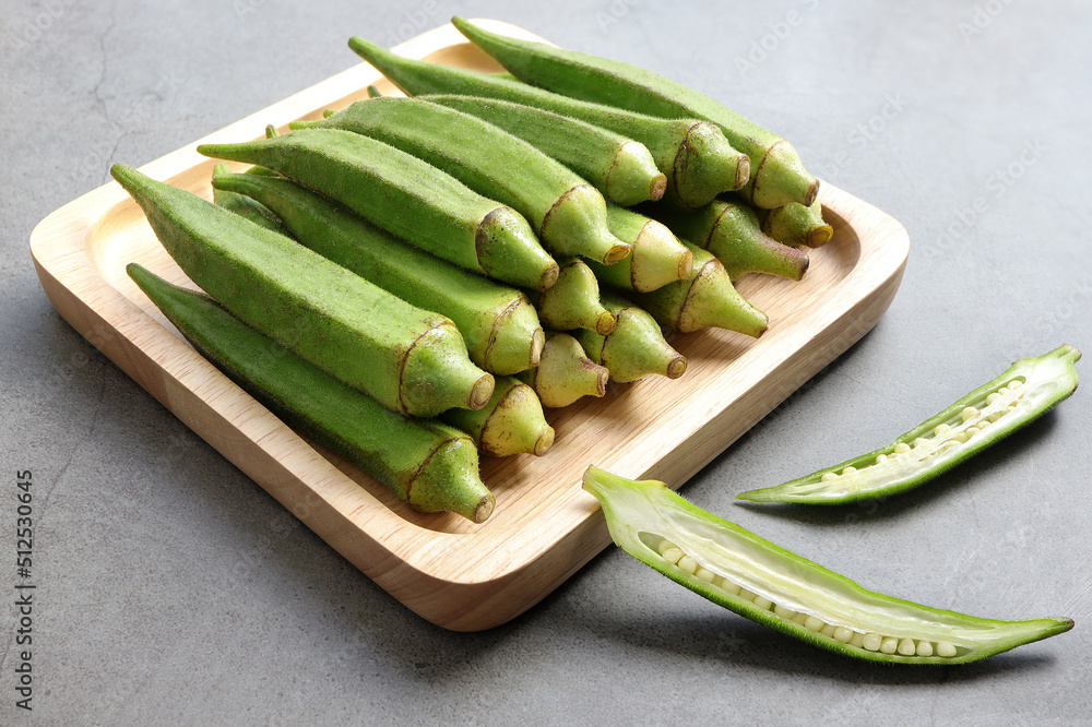 Close up of Fresh okra fruits or abelmoschus esculentus in wooden plate on the table. Close up of Fresh okra fruits or abelmoschus esculentus in wooden plate on the table.