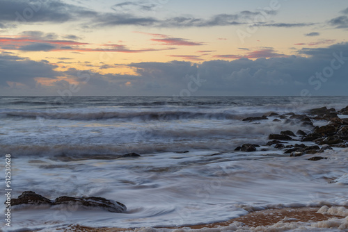 Sunrise seascape with sea foam and rain clouds