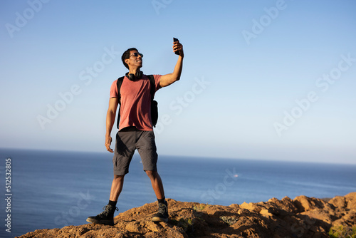 Young man taking selfie photo on a road trip. Man making memories on the mountain.. © JustLife