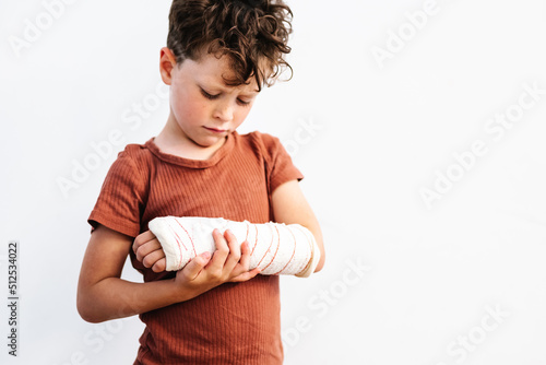 Unhappy boy with broken arm in plaster bandage photo