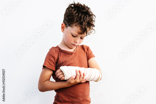 Unhappy boy with broken arm in plaster bandage photo
