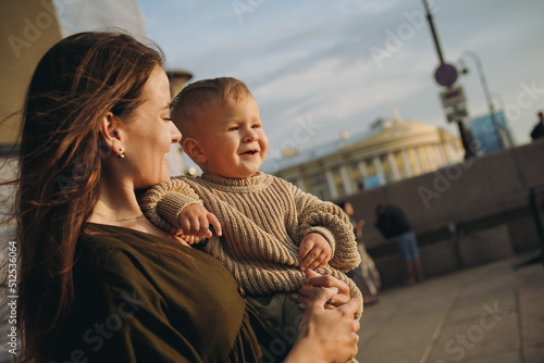 beautiful caucasian young mom holding baby son at the quay of city Saint-Petersburg, Russia