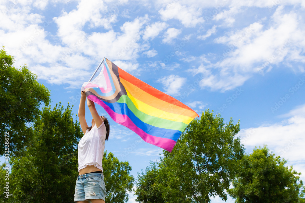 Pride month. Young lesbian girl waving the lgbtiq+ flag on the pride day. Celebrating the lgbt lesbian women rights.