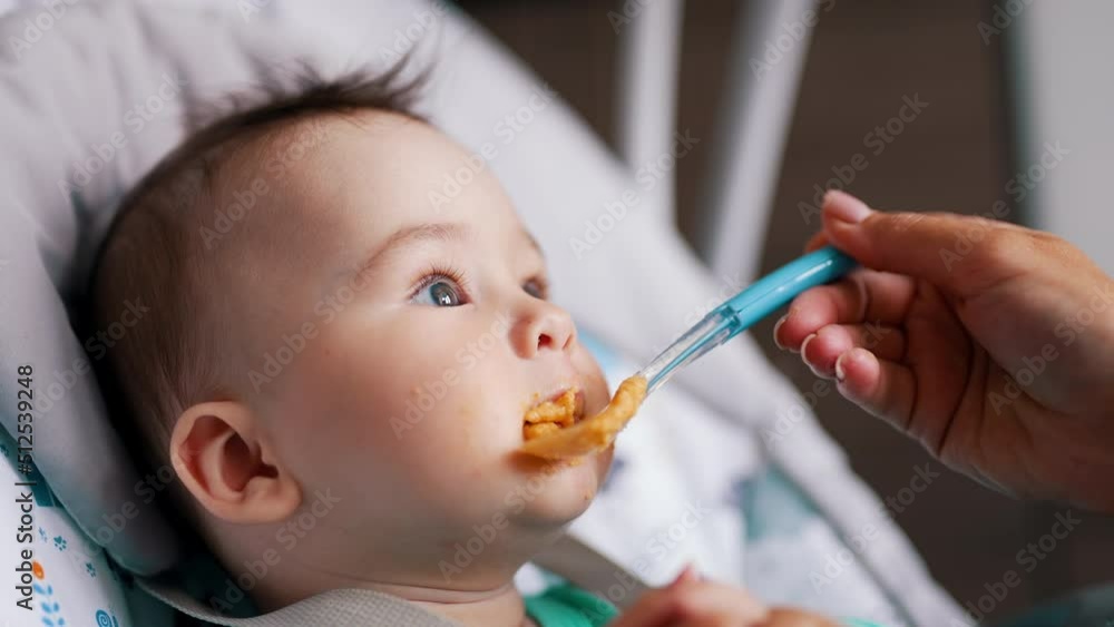 Healthy little baby boy being active during meal. Mommy gives her son some food and child rises hands and waves them. Healthy little baby boy being active during meal. Mommy gives her son some food and child rises hands and waves them.
